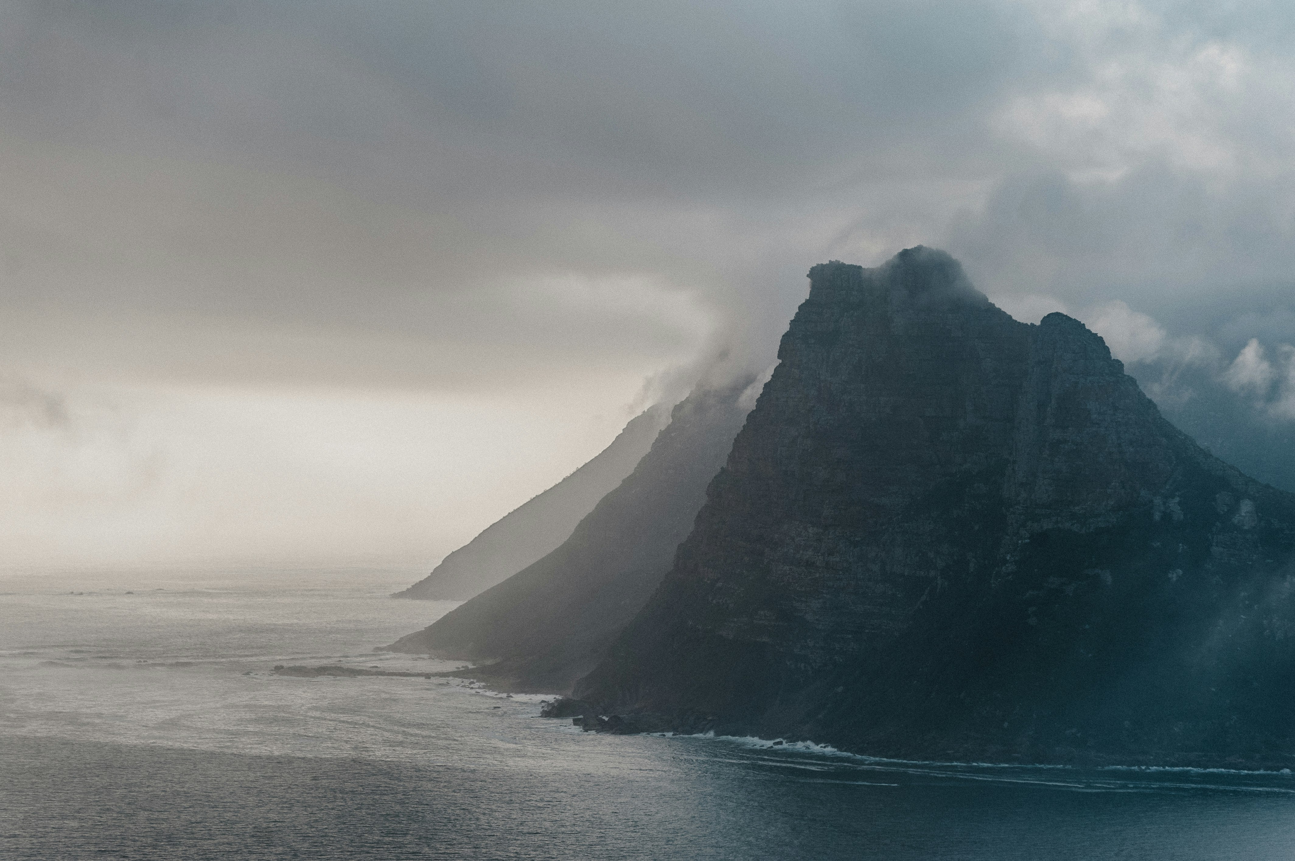 aerial photography of rock mountain island with ocean water view during daytime