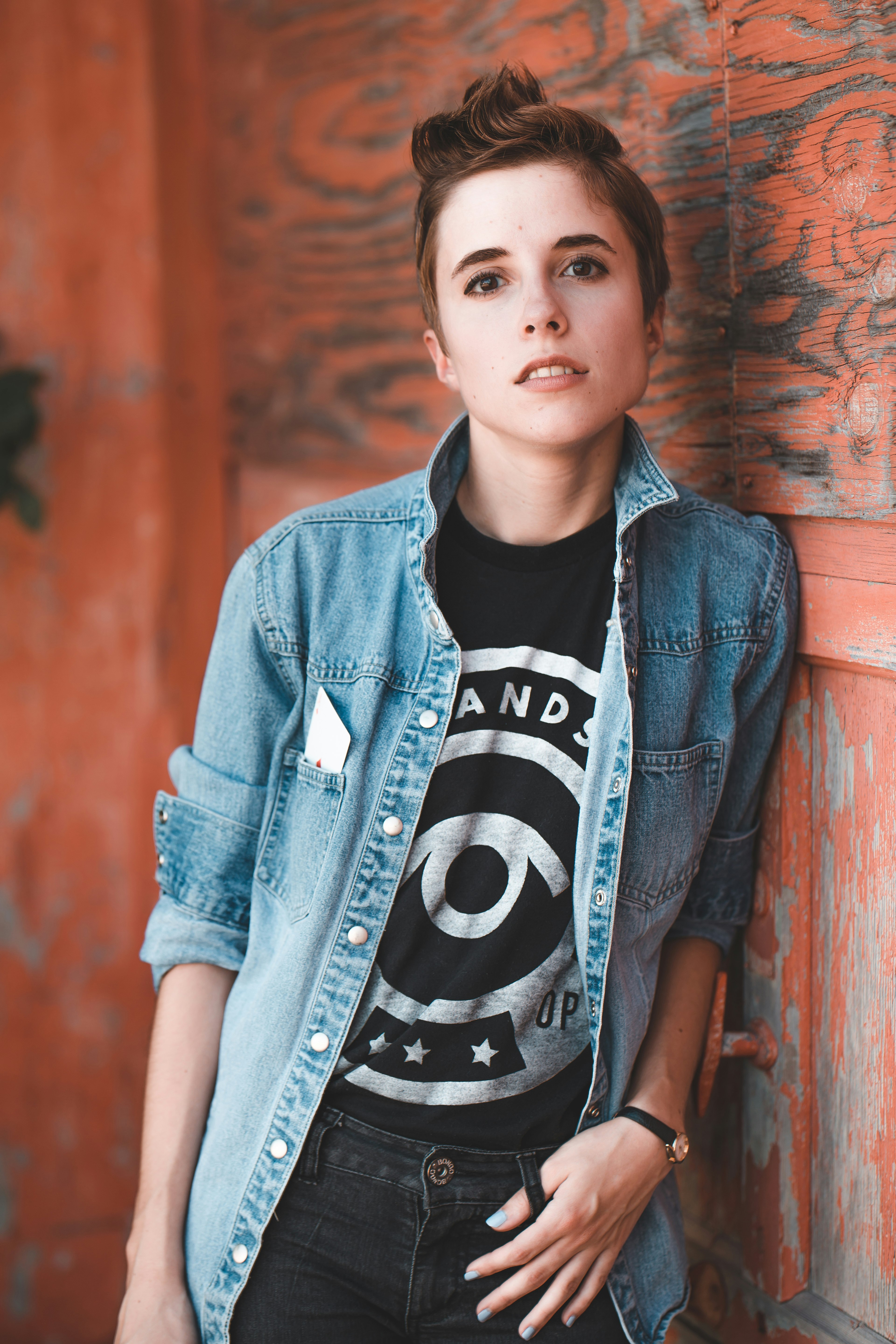 portrait photography of woman leaning beside on brown wooden wall