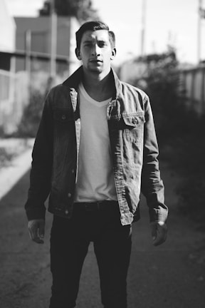 Casual men’s outfit featuring a denim jacket and white sneakers in an urban setting.