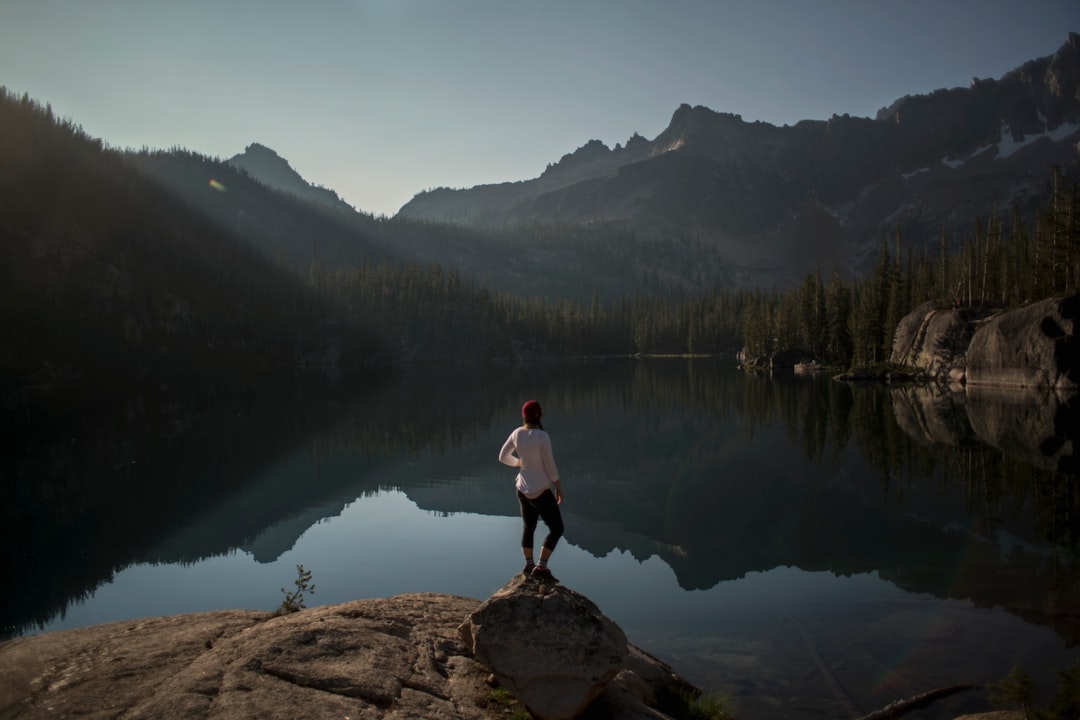 person standing on cliff near lake