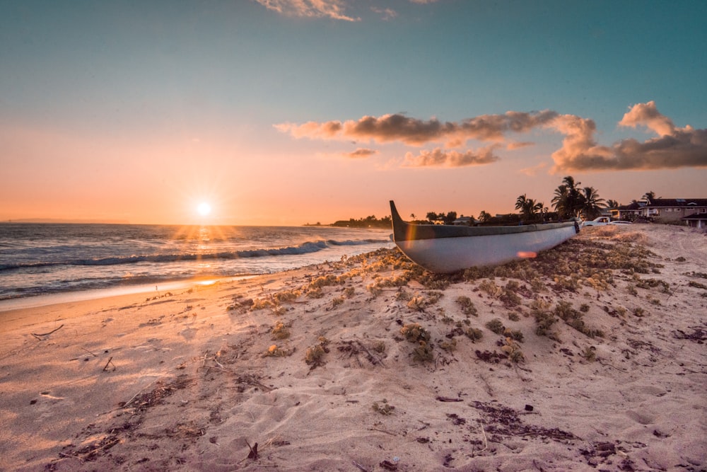 canoe on seashore under cloudy sky