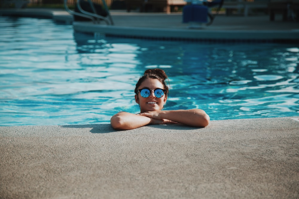 Frau trägt tagsüber Sonnenbrille im Schwimmbad