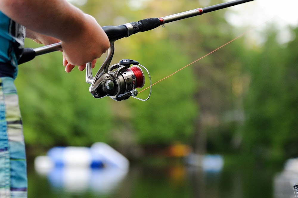 persona che tiene in mano il mulinello da pesca