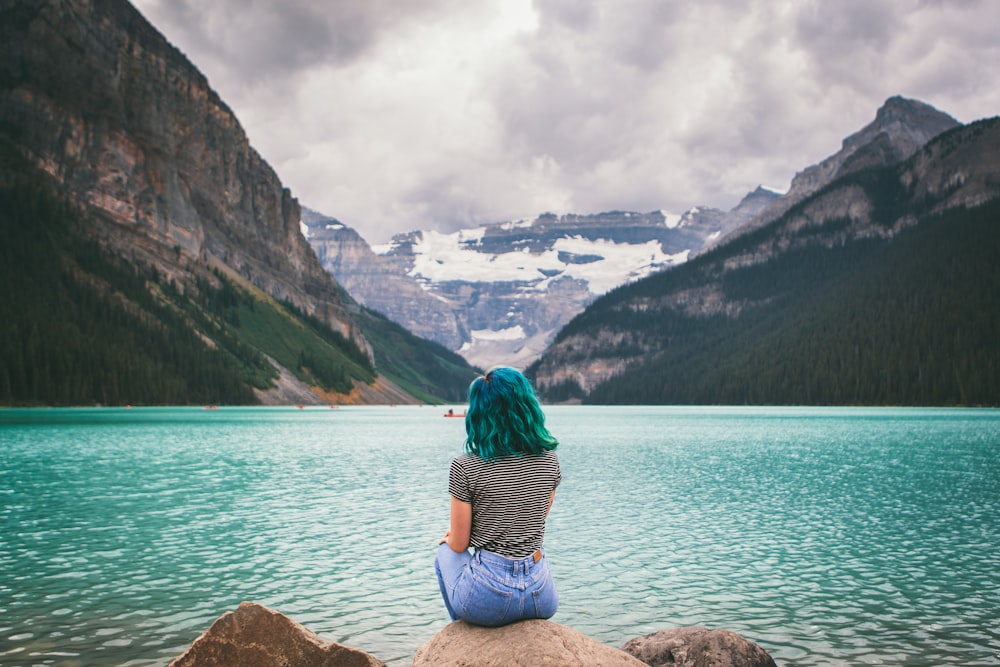 woman sitting on chair near body of water