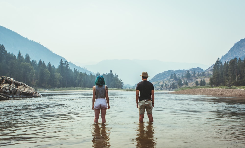 man and woman standing on river