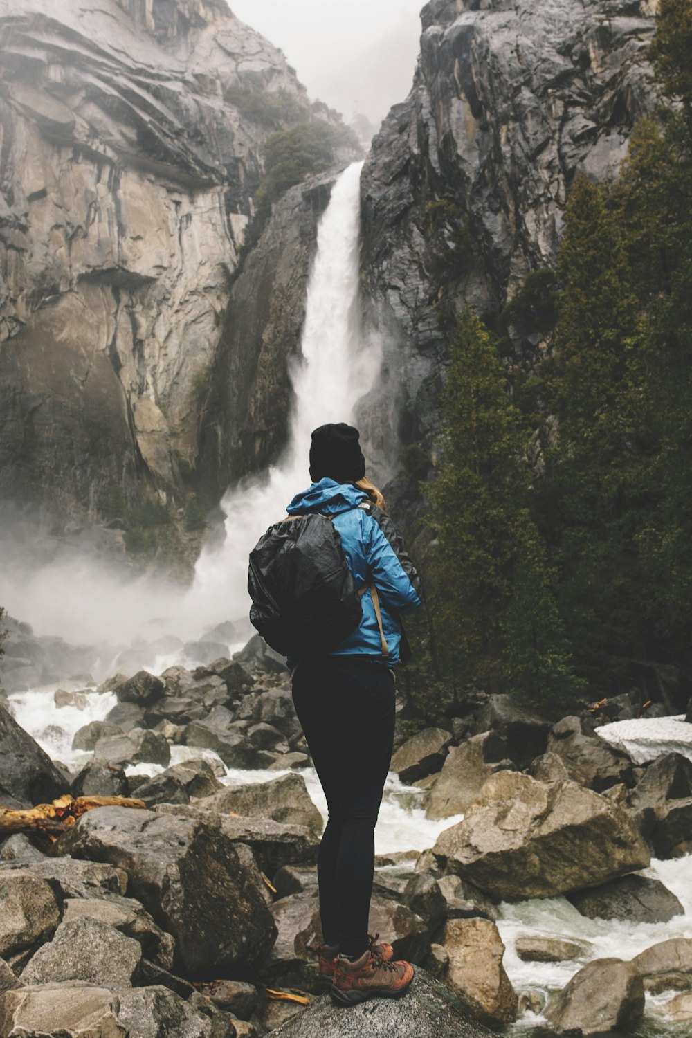 woman standing on rock facing waterfalls