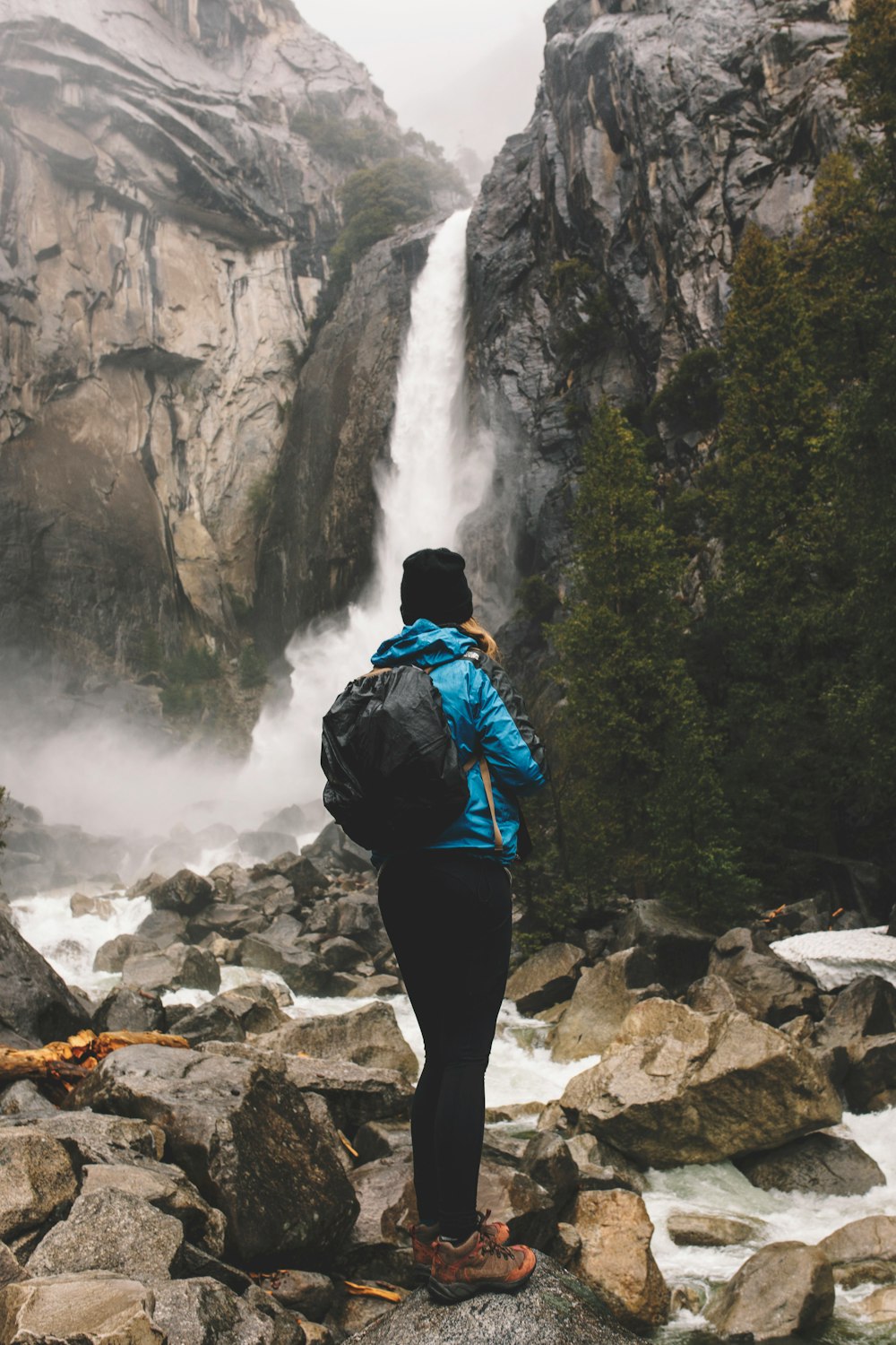 woman standing on rock facing waterfalls