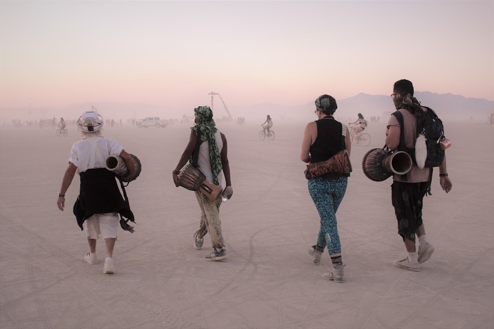 four person walking while carrying drums