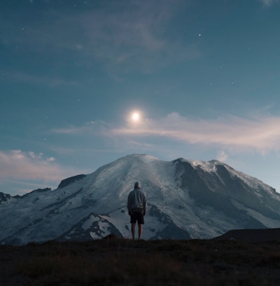 man standing on grass field overlooking mountain