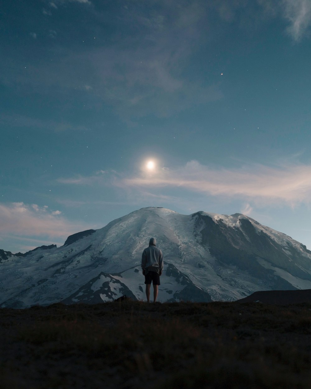 uomo in piedi sul campo di erba che domina la montagna