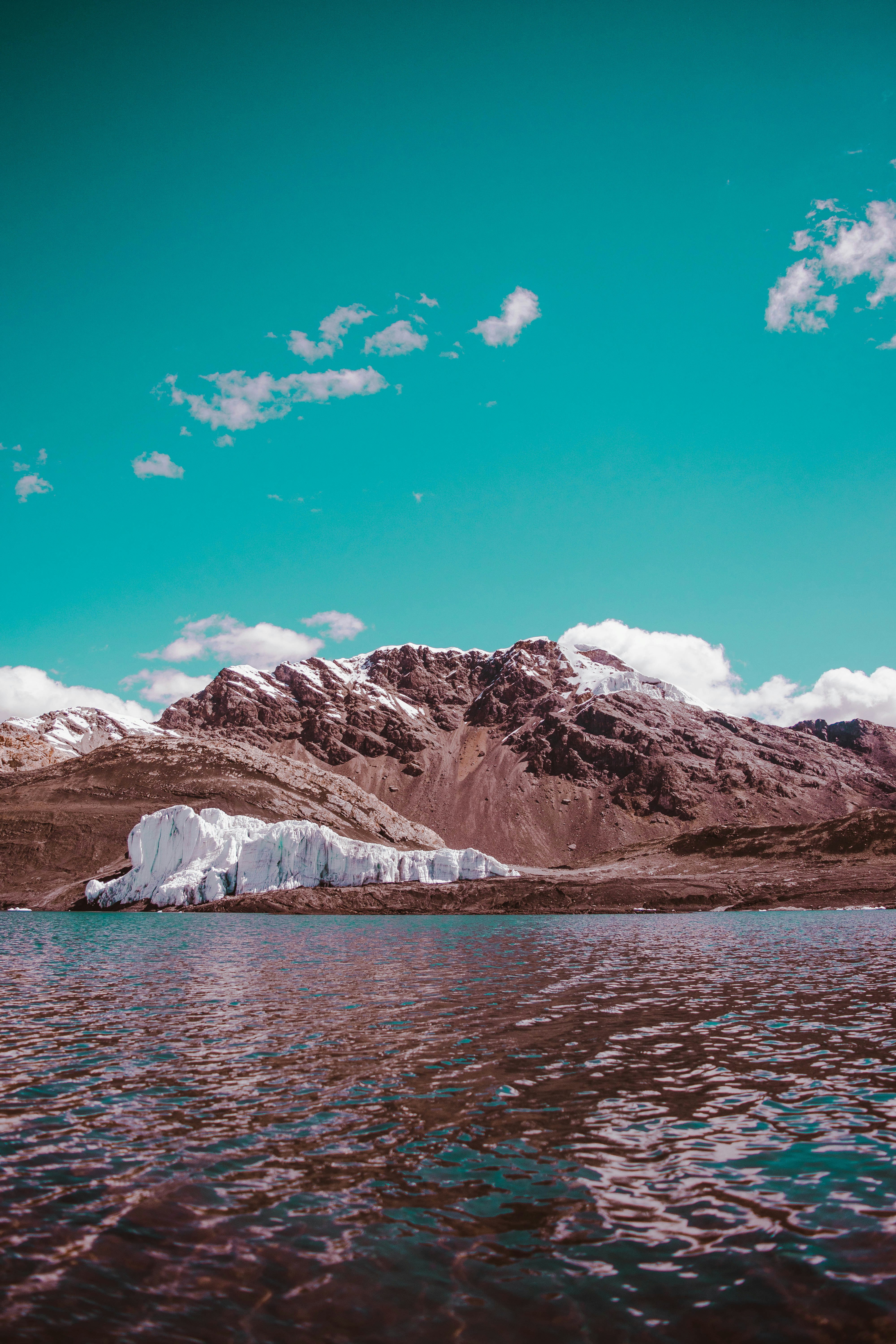 brown and white mountain near body of water