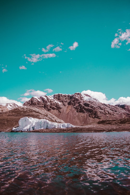 brown and white mountain near body of water in Pastoruri Glacier Peru