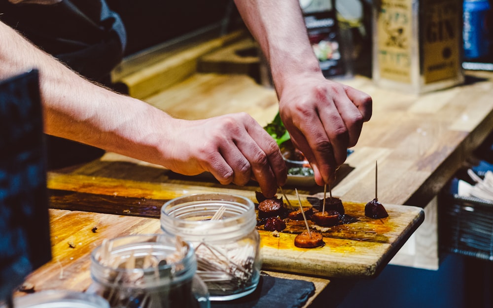 person preparing bite-sized sausage on board