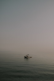 A small fishing boat floating on calm waters of West Fox Lake early in the morning.