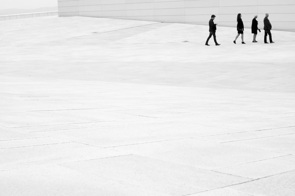 four people walking near wall