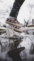Close-up of running shoes splashing through puddles during a lively group run.