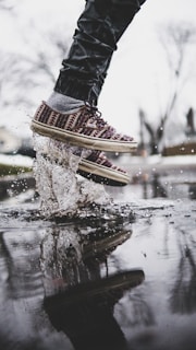 Close-up of running shoes splashing through puddles during a lively group run.