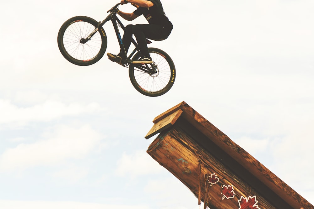 man riding on BMX bike on mid air during daytime