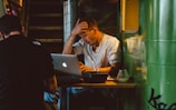 man in front of silver MacBook while scratching his head