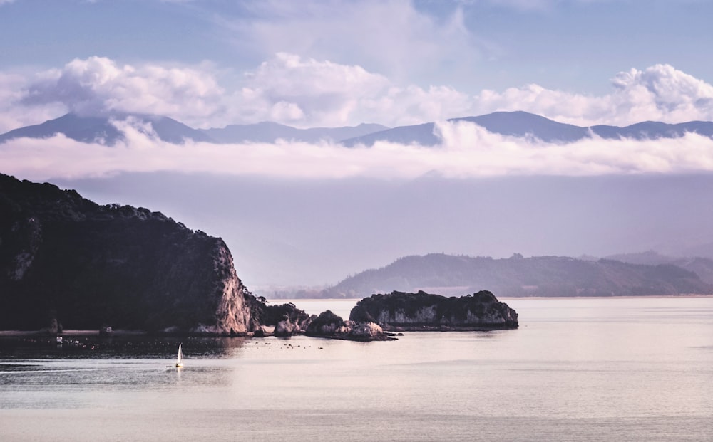 cliff on beach under cumulus clouds