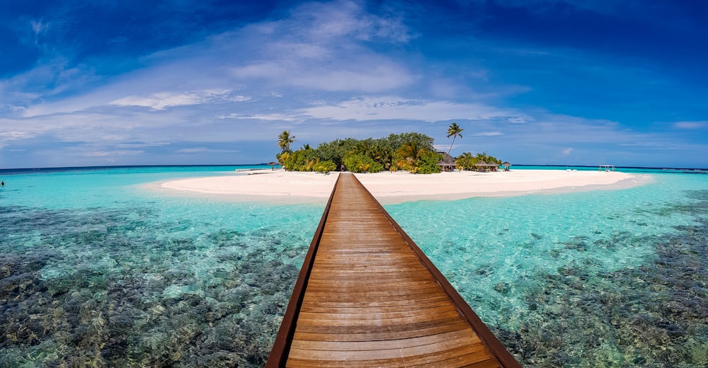 brown dock on body of water under blue sky