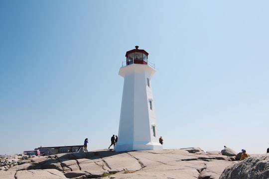 white and black lighthouse under blue sky in Nova Scotia Canada