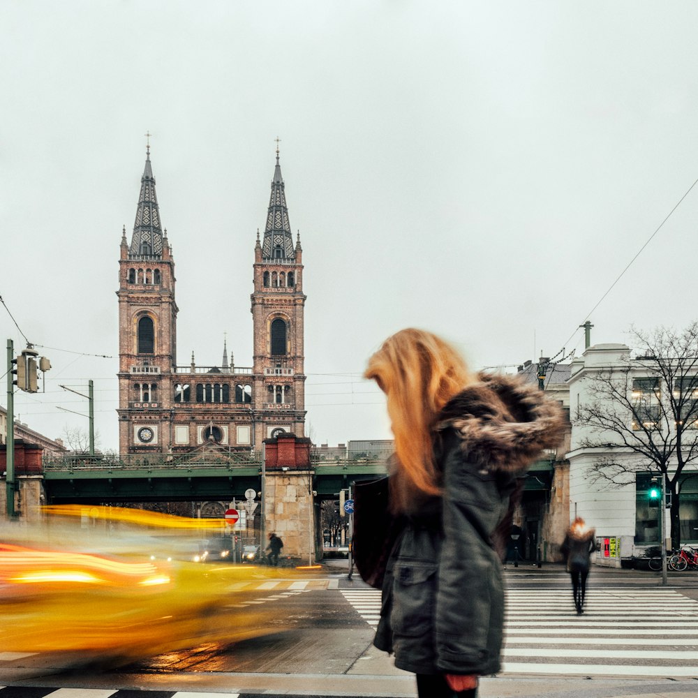 Mujer rubia con abrigo de invierno de pie en la fotografía de lapso de tiempo al borde de la carretera