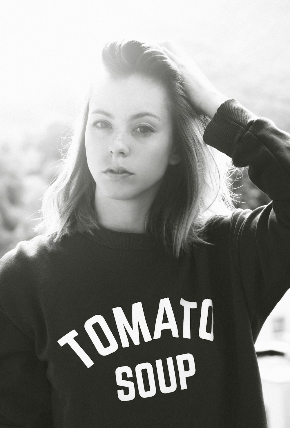 grayscale photo of woman wearing sweatshirt holding her hair