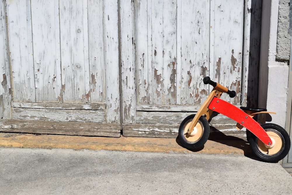 toddler's orange bicycle park beside door