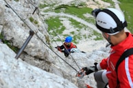 A climber wearing a helmet and gloves, preparing gear before ascent.