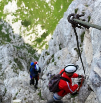 man climbing on gray mountain via ferrata portugal