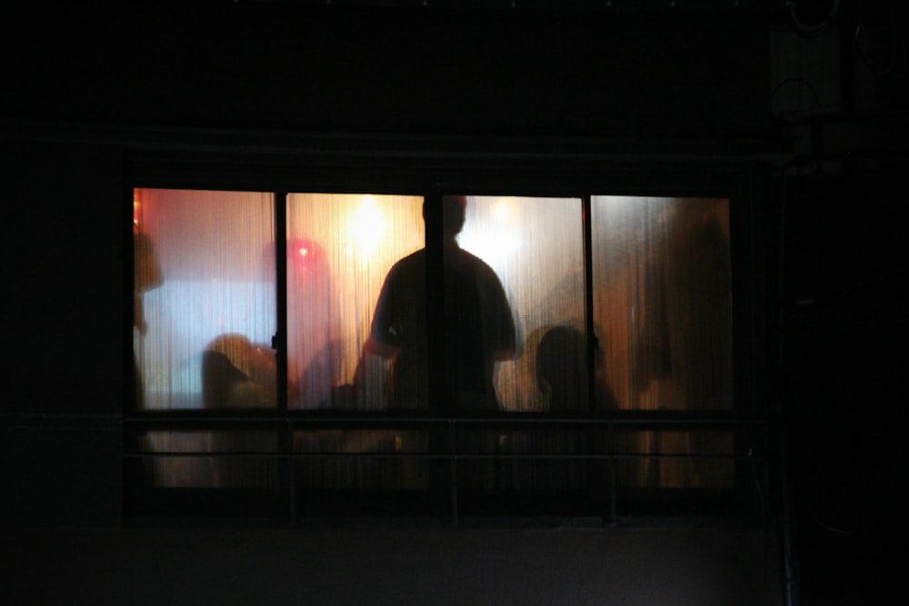 silhouette photo of man standing window pane