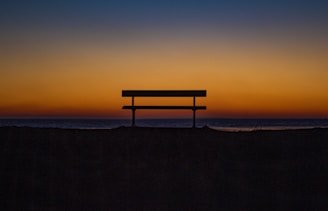 bench near shoreline during sunset