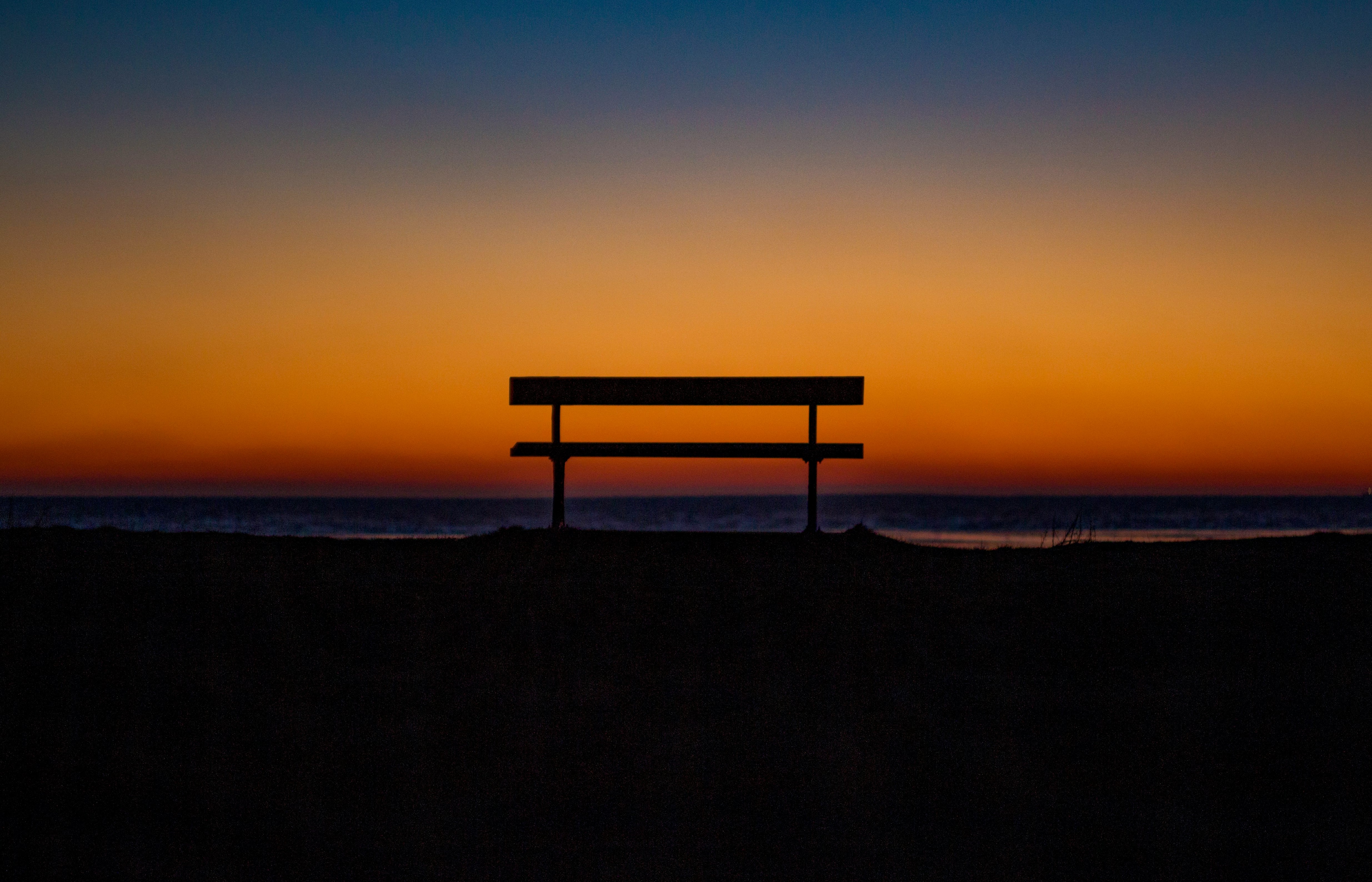 bench near shoreline during sunset