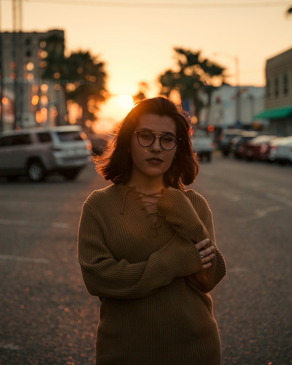 Frau steht während der goldenen Stunde auf der Straße in der Nähe von Fahrzeugen