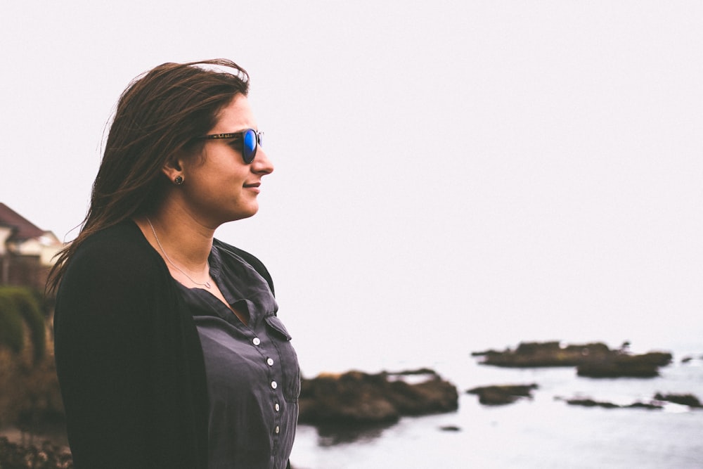 woman in black cardigan standing in front of beach during daytime