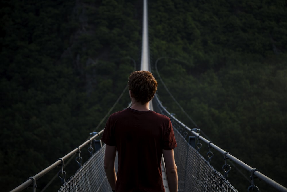 man standing alone on hanging bridge