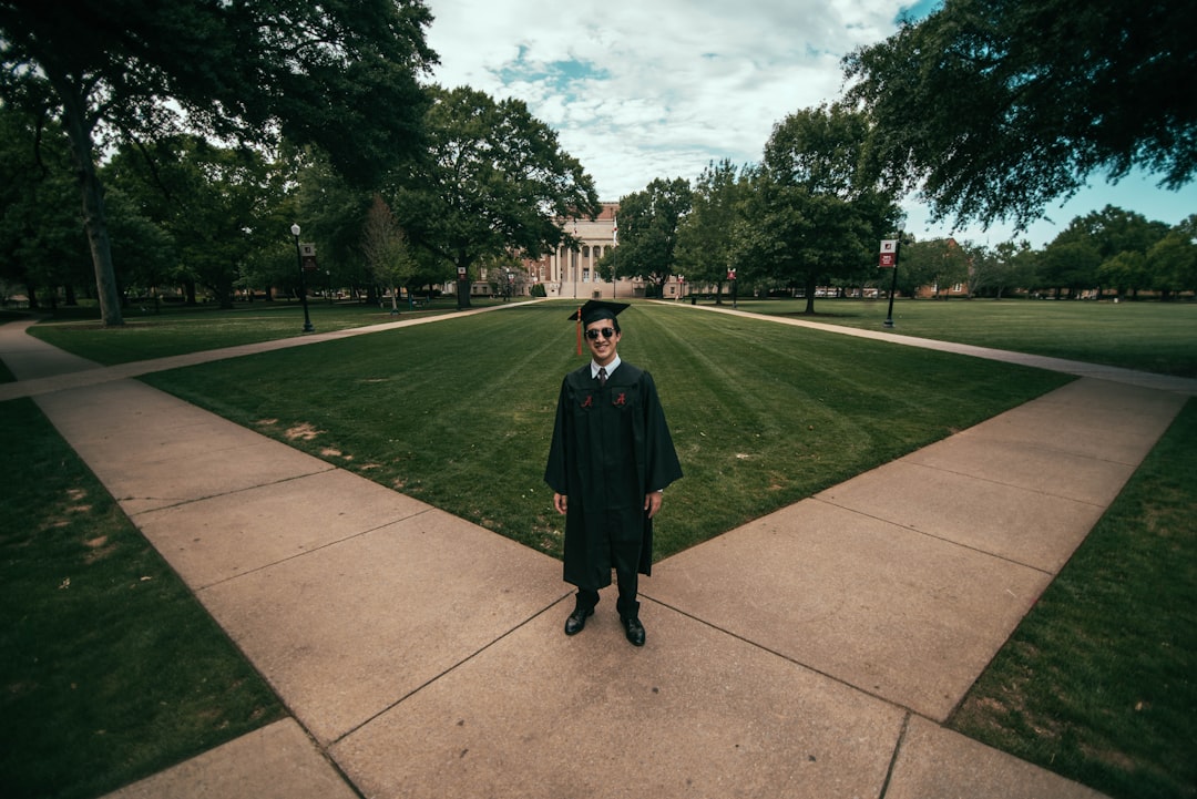 man wearing academic gown standing on green field