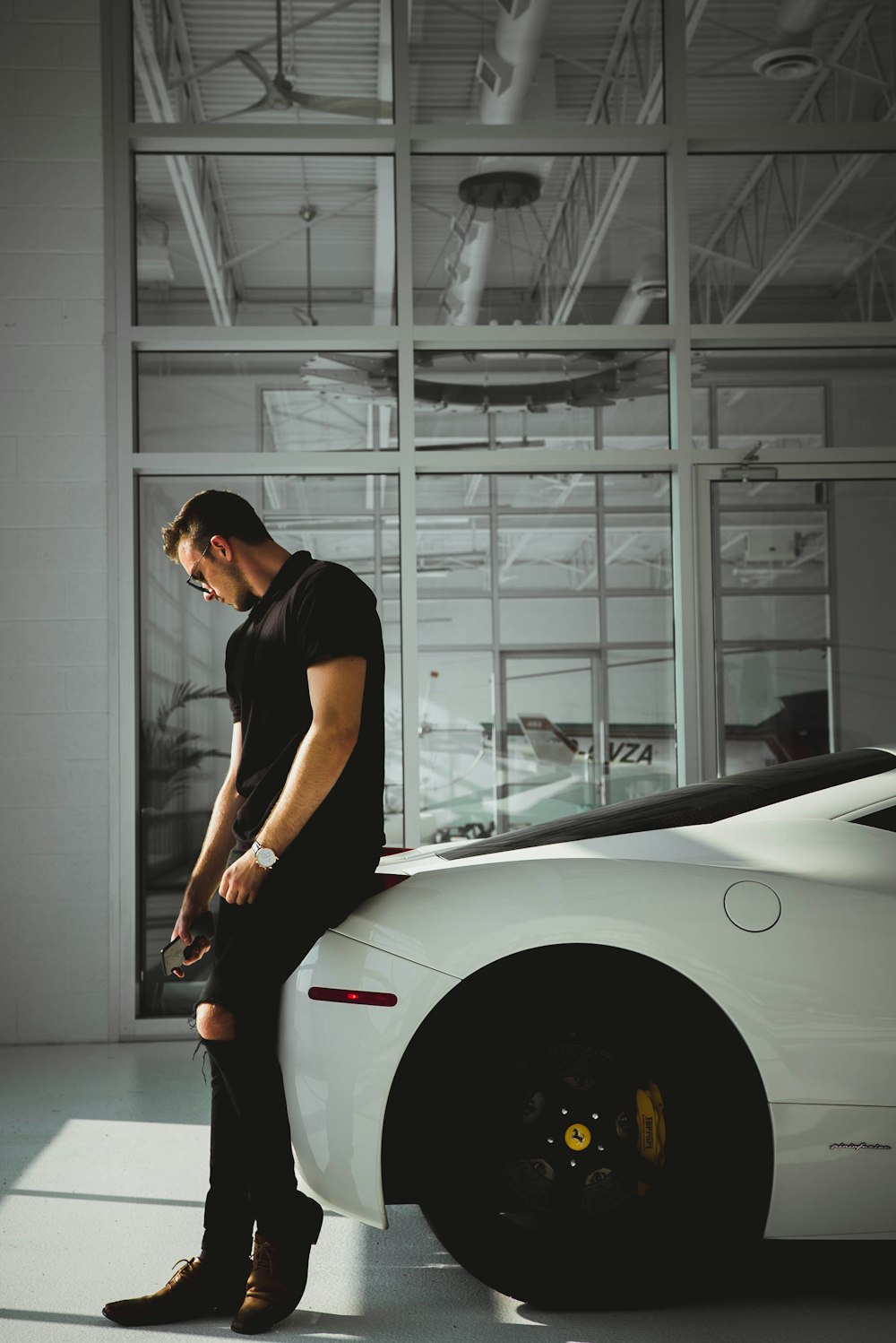 man sitting on car near glass window