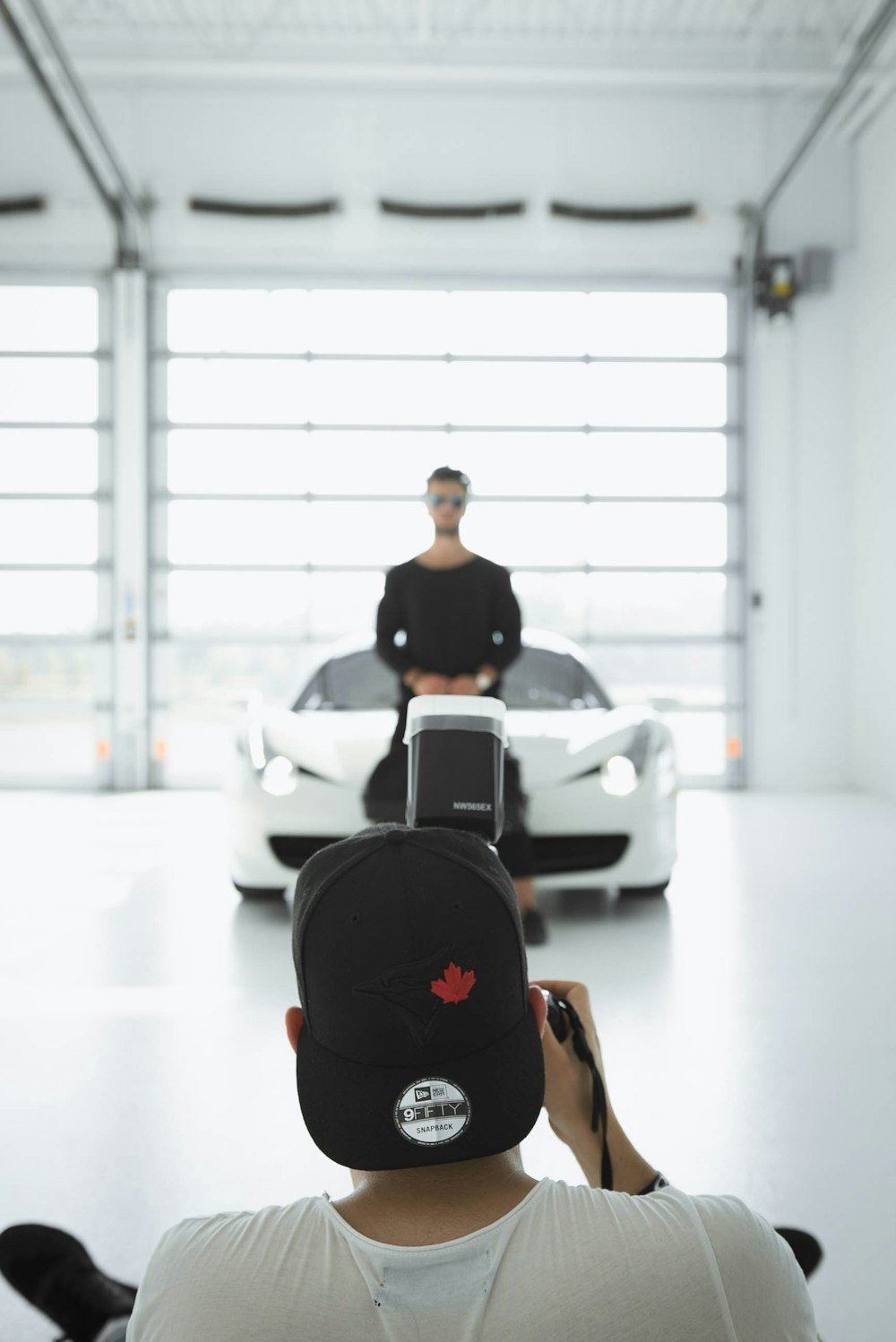 man taking a picture of standing man in front of car inside room