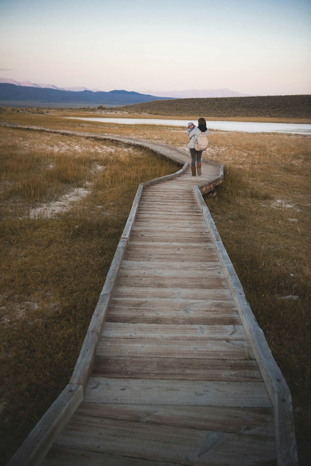 woman holding baby while walking on dock