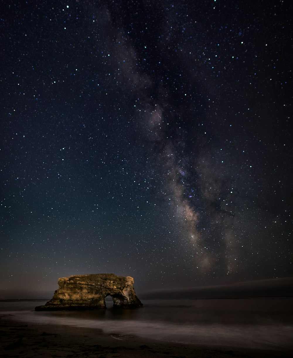 brown rock formation on body of water during nighttime