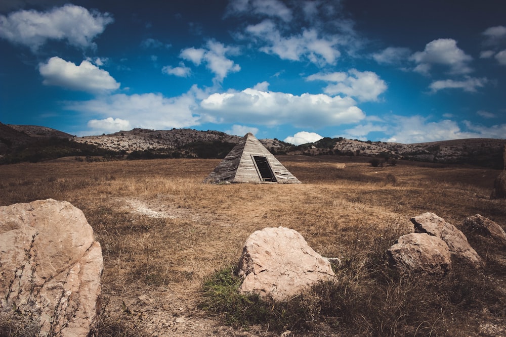 pyramid gray tent on brown field under white clouds