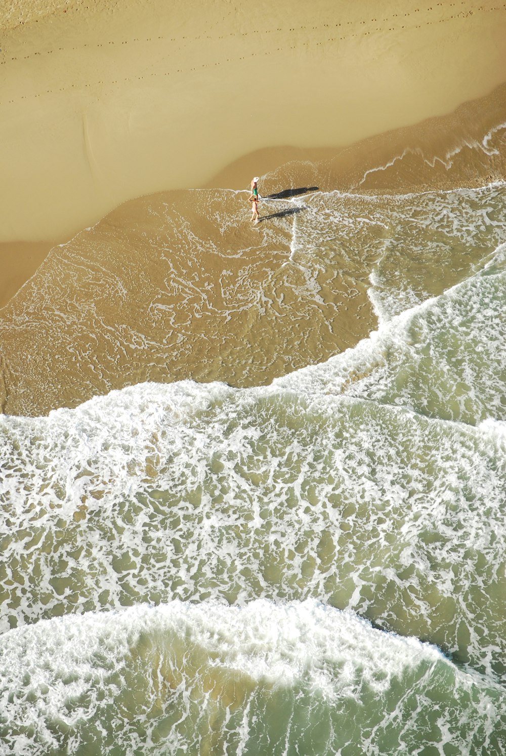 person walking on seashore waves