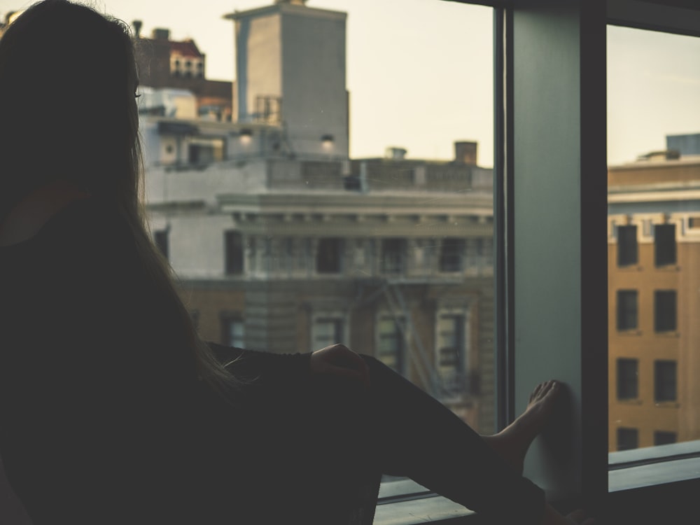 Frau in Schwarz sitzt am Fenster