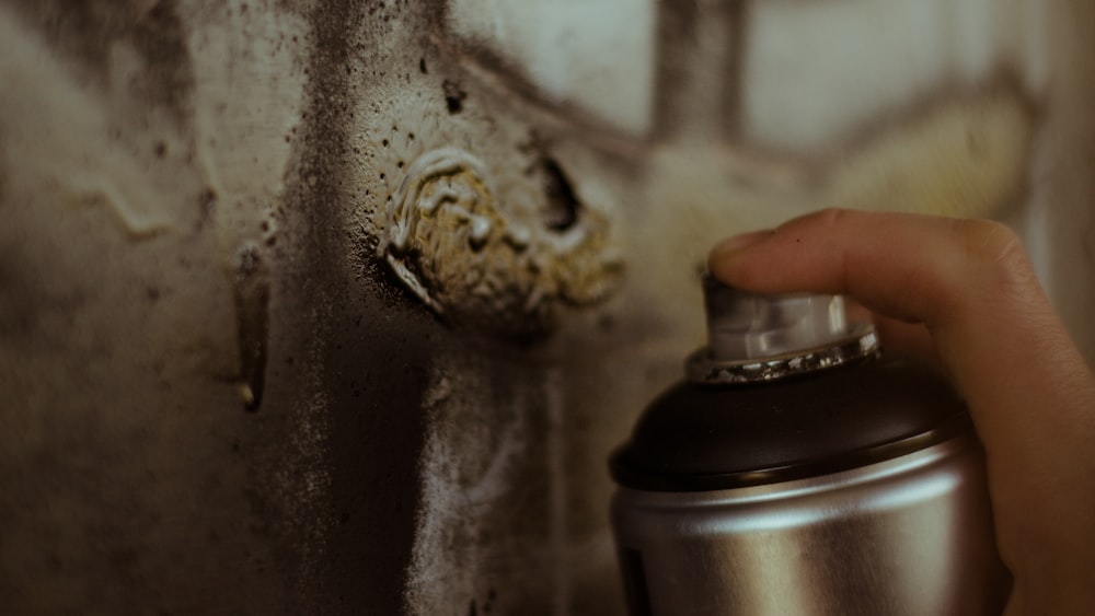 person holding gray spray can