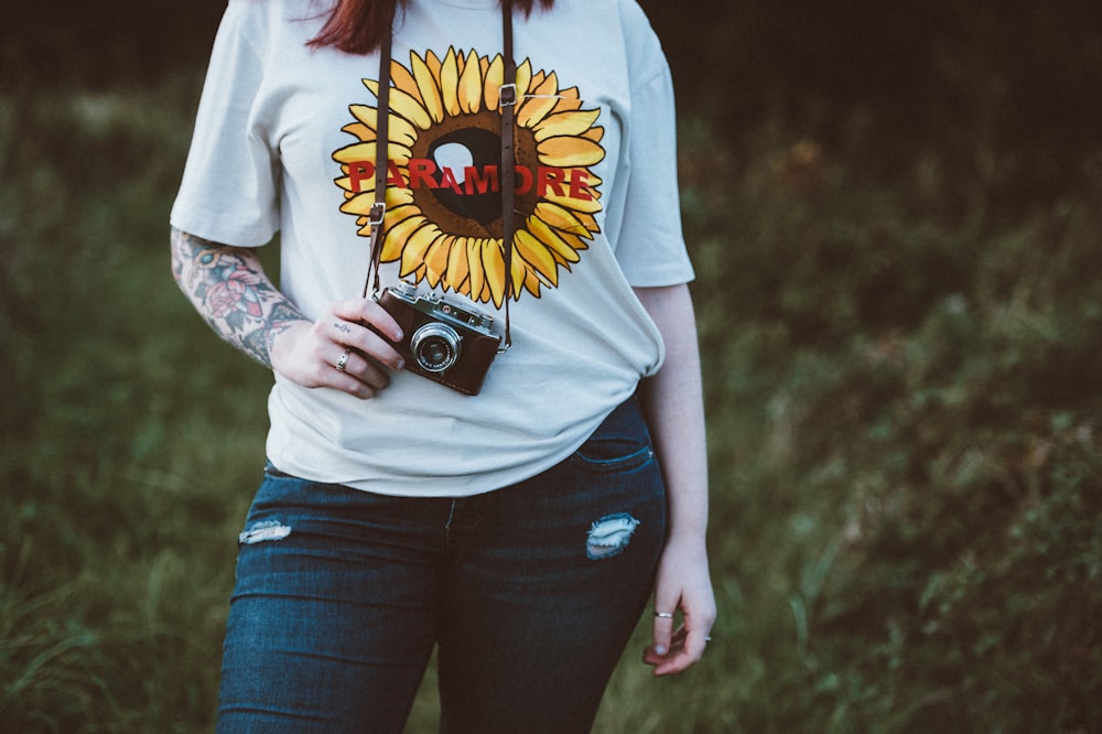woman holding SLR camera standing near grass