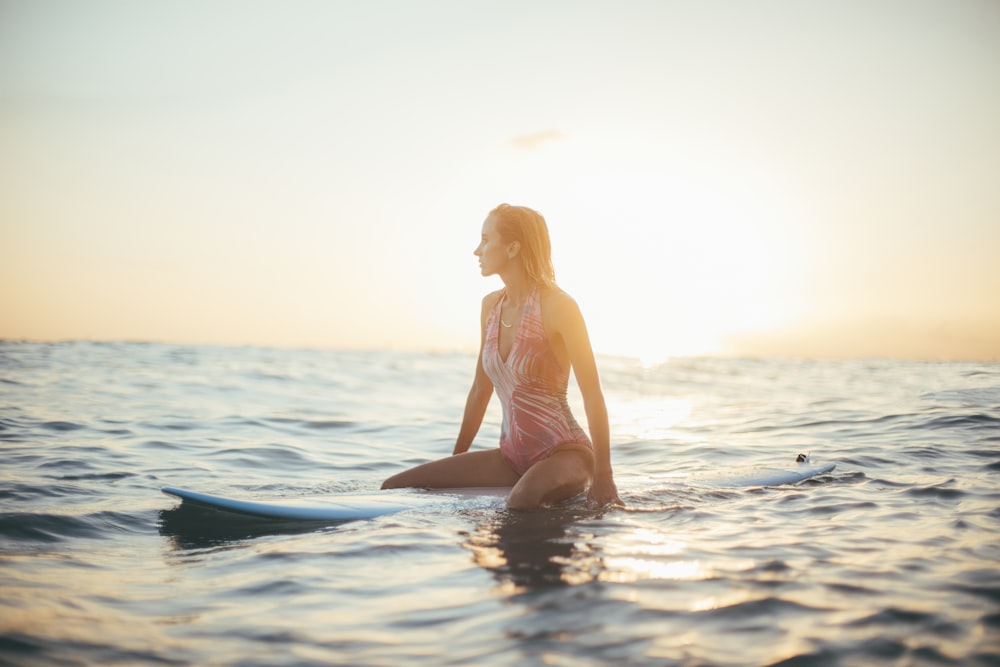 Mujer montando una tabla de surf azul en un cuerpo de agua