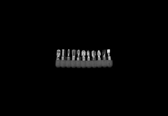 A set of colorful screwdriver heads neatly arranged next to a sturdy screwdriver handle on a metal surface.