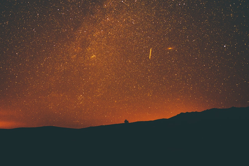 silhouette of mountain under milky way at night time